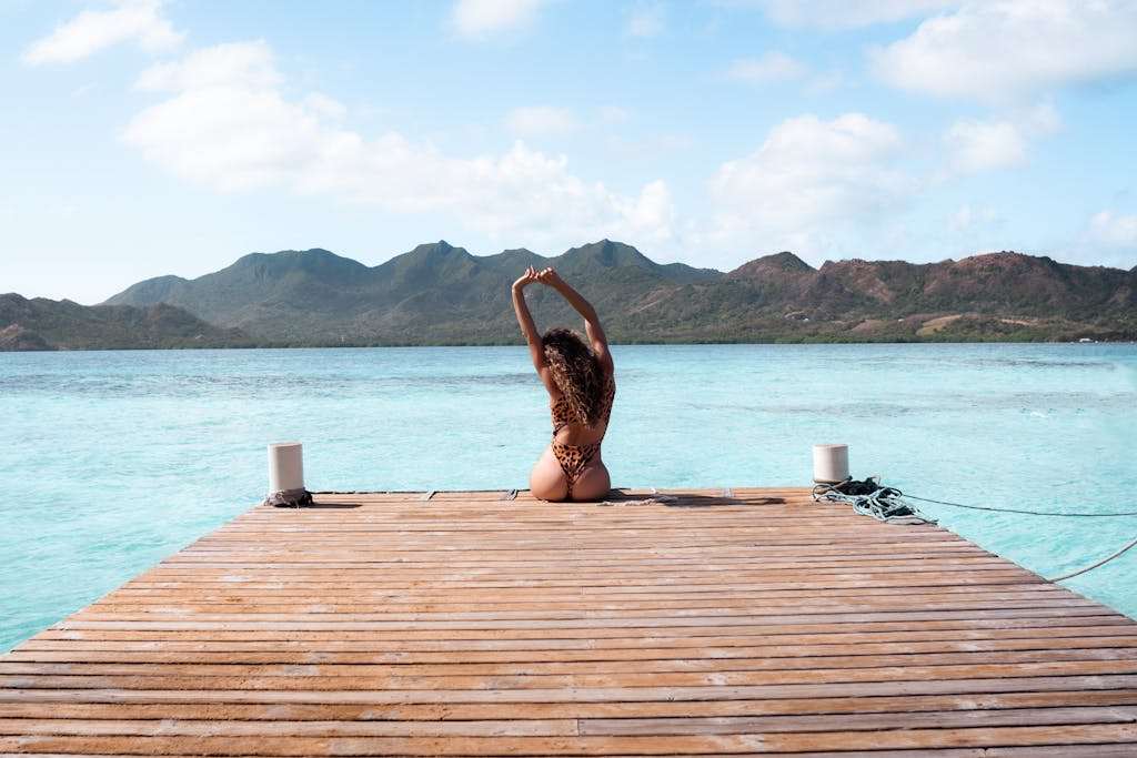 Woman sitting on a pier in Caribbean Colombia with turquoise waters and mountains.